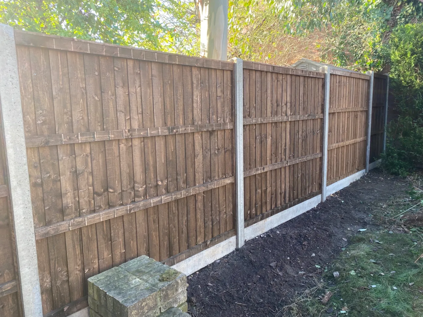 Brown closeboard fence panels fitted with concrete posts and gravel boards in a garden